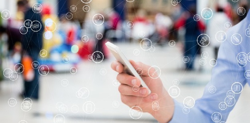 En la información vinculada al desarrollo de soluciones informáticas en el CeSPI, una mano masculina sostiene un teléfono celular con fondo de una ciudad. Gráficos de conectividad se superponen a la imagen.